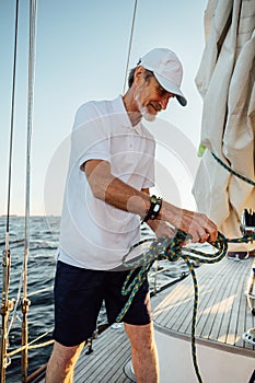 Mature yachtsman adjusting the rope