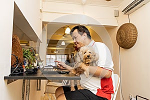 Matured Asian business man work from home accompanied by pet dog during lockdown