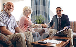 Matured male physician shaking hand and smiling at retirement home