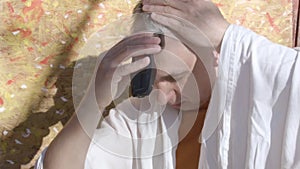 A matured man cutting his hair with electric razor, sitting outdoor