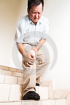 Matured man suffering acute knee joint pain descending stairs