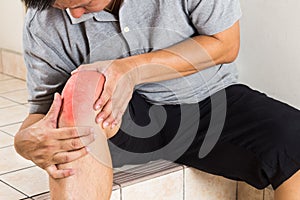 Matured man suffering painful knee joint seated on steps