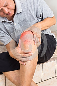 Matured man suffering painful knee joint seated on steps