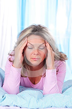 Matured woman in bed with strong headache