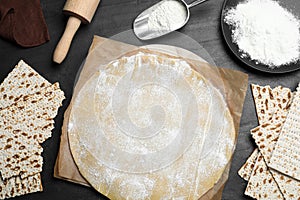 Matzos and raw dough on black table, flat lay