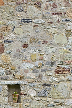 Mauer aus Naturstein mit Pflanzentopf im Hochformat in Italien