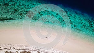 Maumere - A drone shot of a couple sitting on a white sand beach