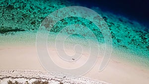 Maumere - A drone shot of a couple sitting on a white sand beach photo