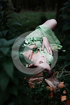 Mavka. A beautiful woman in a green dress is walking through the forest.