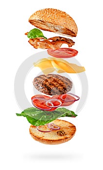 Maxi burger preparation with flying ingredients isolated on white background. Clipping path