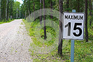 A maximum 15 speed limit sign along a gravel road