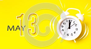 May 13rd. Day 13 of month, Calendar date. White alarm clock with calendar day on yellow background. Minimalistic concept of time,