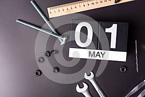 May 1st. Day 1 of may month, calendar on black background with workers tools. Labour day.