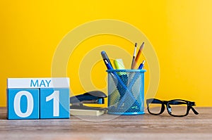 May 1st. Day 1 of month, calendar on business office table, workplace at yellow background. Spring time