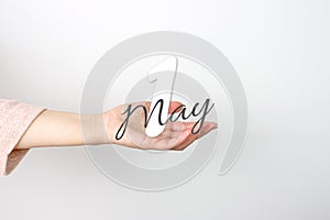 May 1st . Day 1 of month, Calendar date. Calendar Date floating over female hand on grey background. Spring month, day of the year