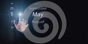 May 1st . Day 1 of month, Calendar date. Hand click luminous icon PLAY and DATE on dark blue background. Spring month, day of the