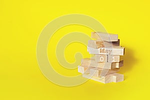 May 1st . Day 1 of month, Calendar date. Wooden blocks folded into the tower with month and day on yellow background, with copy