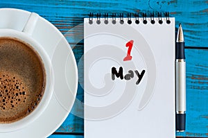 May 1st. Day 1 of month, calendar on white notepad with morning coffee cup at work place background. Spring time, Top