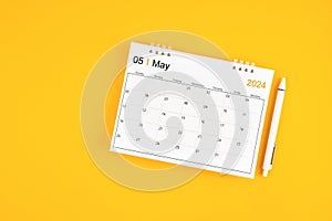 May 2024, Monthly desk calendar for 2024 year and pen on yellow background