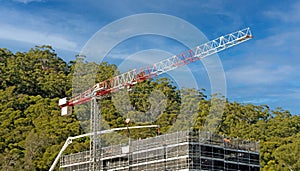 May 3, 2021. Concrete Boom Pump delivering material to new building site with a tower crane and blue cloudy sky backdrop at 56-58