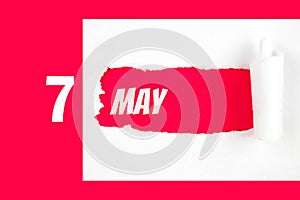 May 7th. Day 7 of month, Calendar date. Red Hole in the white paper with torn sides with calendar date. Spring month, day of the