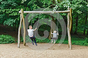 Father And Son Having Fun On Swing In Playground in park