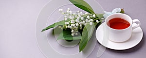 May Lily flowers with tea cup on gray background. springtime tender bouquet. Floral romance background. Spring, summer breakfast