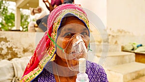 Old woman admitted in hospital and inhaling emergency oxygen with canula mask photo