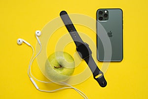 May 01, 2020, Rostov, Russia: Smartphone iPhone 11 Pro of midnight green color, wired headset and Apple Watch S4 with green ripe