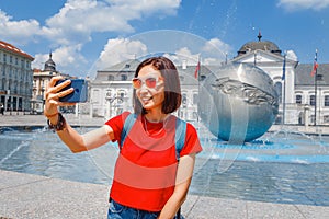 Tourist woman doing selfie and photographing palace residence of President and fountain