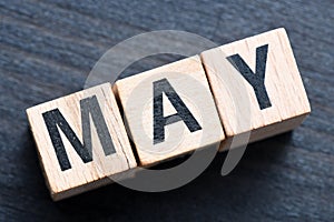 MAY word arranged with wooden letters on a black background