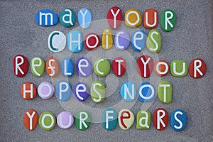 May your choices reflect your hopes, not your fears, life quote composed with multi colored stone letters over beach sand