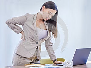 Maybe its time for a new office chair. a young businesswoman experiencing back pain while working in an office.