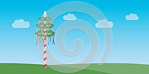 maypole with colorful ribbons on green meadow
