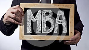 MBA written on blackboard, business person holding sign, business education photo