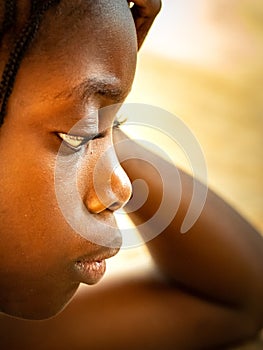 Close up upset thoughtful African teenage girl sitting alone, looking in distance, thinking about teen problem, first love or