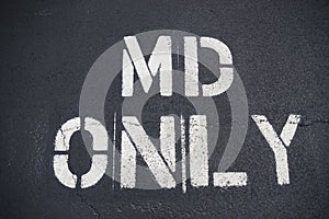MD Only lettering on asphalt parking spot