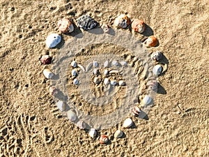 Me letters made in heart shape of Seashells on the sand beach.