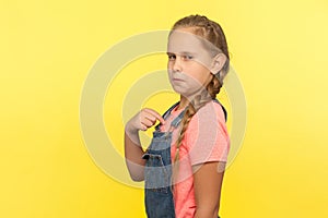 This is me! Portrait of egoistic self-confident little girl in denim overall pointing herself and looking with arrogance