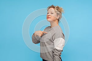 This is me! Selfish haughty woman with short curly hair in sweatshirt pointing herself, feeling supercilious arrogant photo