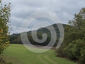 Meadow, fields and forest with view of medieval castle Houska. Autumn, moody sky. Landscape in Kokorinsko, Czech