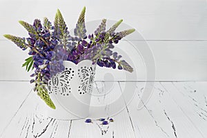 Meadow flowers lupines bouquet in white decorative bucket.