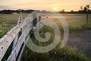 Meadows with wooden fence and rising sun in the early morning