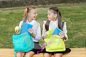 Meal break on fresh air. Happy kids take apples from school bags. Little girls enjoy school break outdoors. Healthy