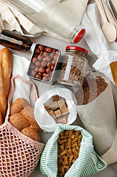 Meal in eco cotton bags, glass and paper packaging on table in the kitchen from market. zero waste shopping concept. ban plastic,