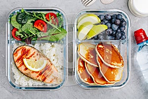 Meal prep containers with salmon, rice, green salad and pancakes, apple, blueberry