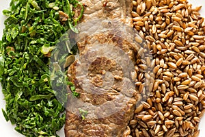 Rye, steak and cabbage meal on white plate. Overhead close up of