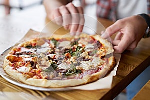 Meal time at pizzeria, man taking a slice of the pizza