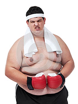Mean and not so lean. An obese young man glaring at the camera and wearing boxing equipment.