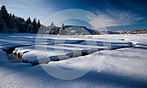 Meandering of the flow of the mountain stream in snowy winter country. Liptovska Luzna, Slovakia